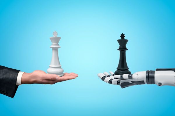 Menschliche Hand und Roboterhand halten jeweils eine Schachfigur als Symbol für Humanübersetzung und KI.